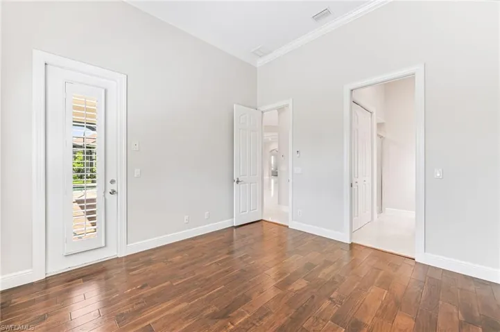 Unfurnished bedroom featuring ornamental molding and dark wood finished floors