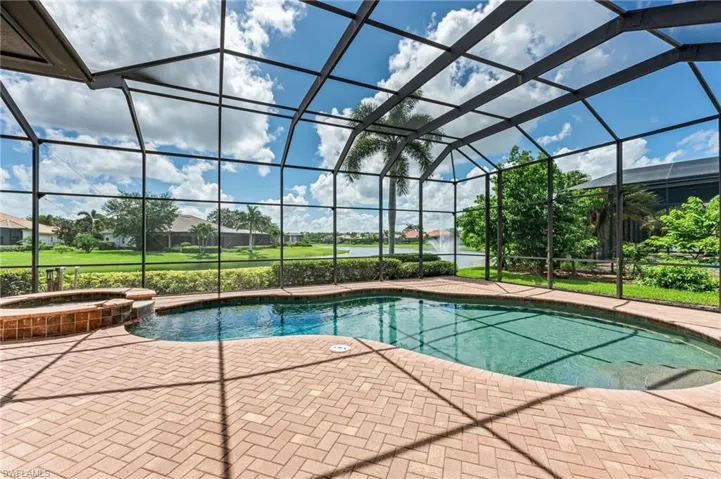 View of pool with glass enclosure, a patio, and a pool with connected hot tub