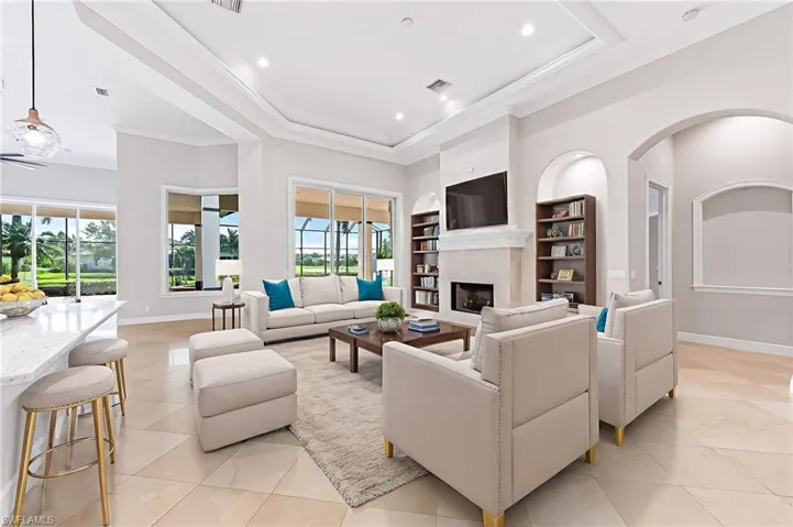 Living room with plenty of natural light, light tile patterned floors, crown molding, a premium fireplace, and built in features