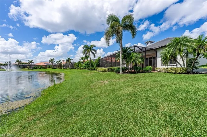 View of green lawn with a water view and a lanai