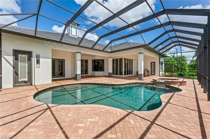 View of swimming pool featuring a patio, a pool with connected hot tub, a lanai, and french doors