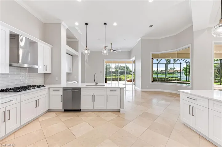 Kitchen featuring appliances with stainless steel finishes, wall chimney exhaust hood, a peninsula, a ceiling fan, and backsplash