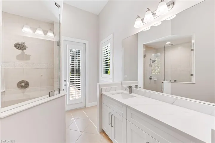 Bathroom with tiled shower, tile patterned floors, and vanity