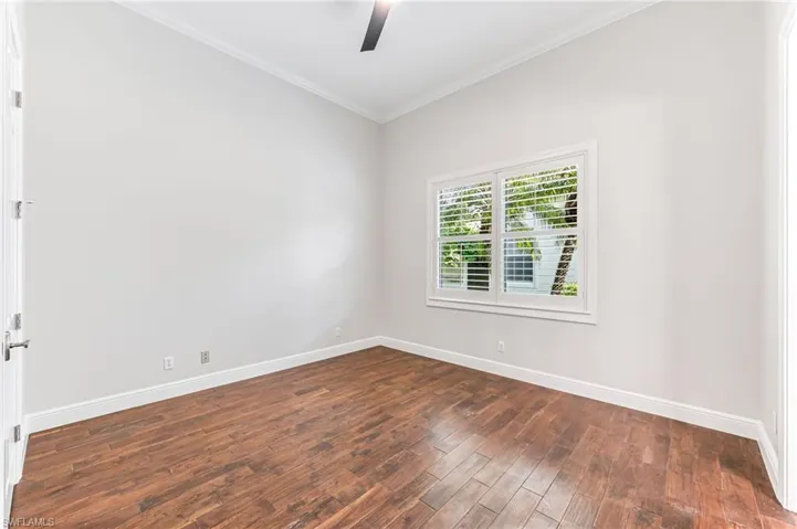 Empty room featuring ornamental molding, a ceiling fan, and dark wood finished floors