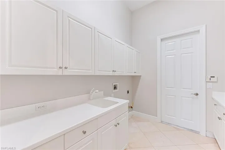 Laundry room featuring electric dryer hookup, cabinet space, washer hookup, and light tile patterned floors