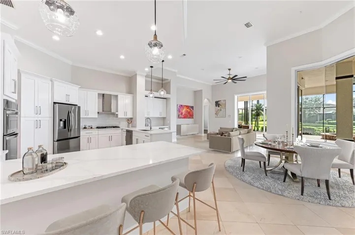 Kitchen with appliances with stainless steel finishes, wall chimney range hood, a peninsula, tasteful backsplash, and crown molding