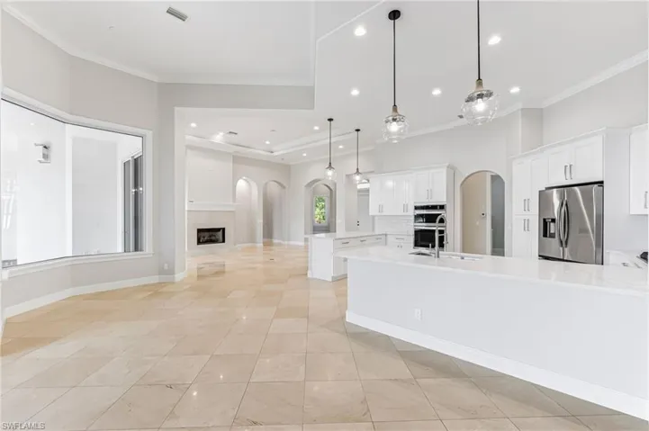 Kitchen with stainless steel appliances, arched walkways, a peninsula, ornamental molding, and light countertops
