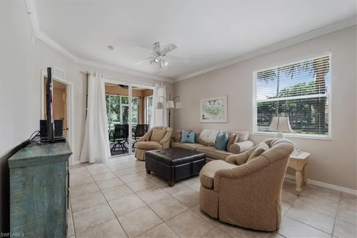 Living room featuring light tile patterned flooring, a ceiling fan, and crown molding