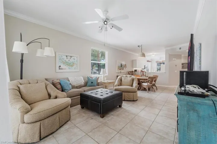 Living area featuring tile patterned floors, ornamental molding, and a ceiling fan