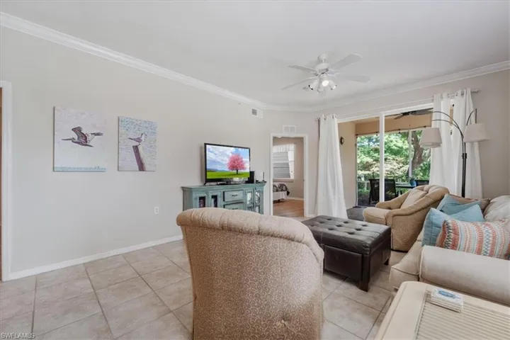 Living area with crown molding, light tile patterned flooring, and a ceiling fan