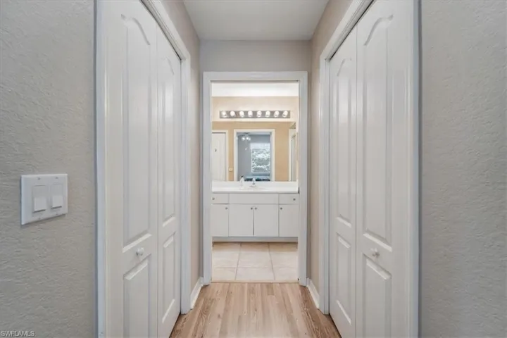 Corridor with a textured wall and light wood-style floors