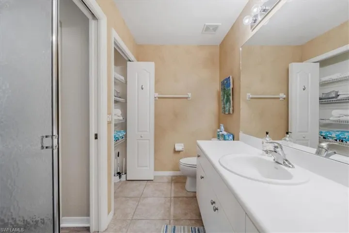 Full bath featuring vanity, light tile patterned floors, a stall shower, and a spacious closet