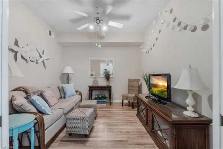 Living room with light wood-type flooring and a ceiling fan