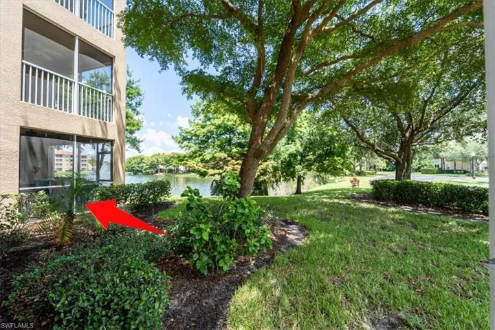 View of green lawn with a sunroom, a balcony, and a water view