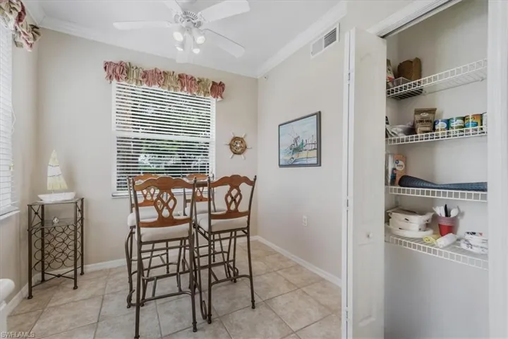 Dining space with crown molding, light tile patterned floors, and a ceiling fan