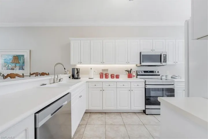 Kitchen featuring appliances with stainless steel finishes, white cabinets, and ornamental molding