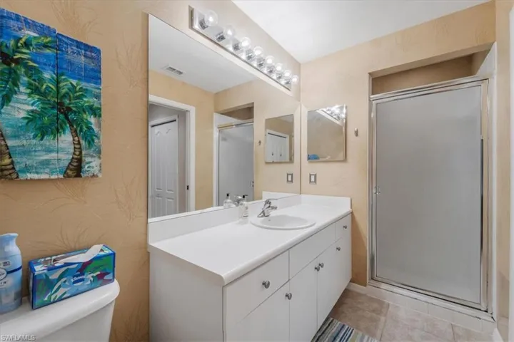 Full bath with vanity, a shower stall, and light tile patterned flooring