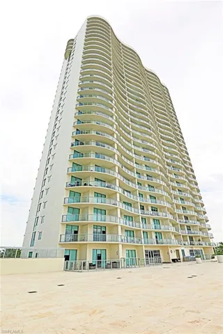 Contemporary high-rise building featuring a striking curved facade with numerous private balconies