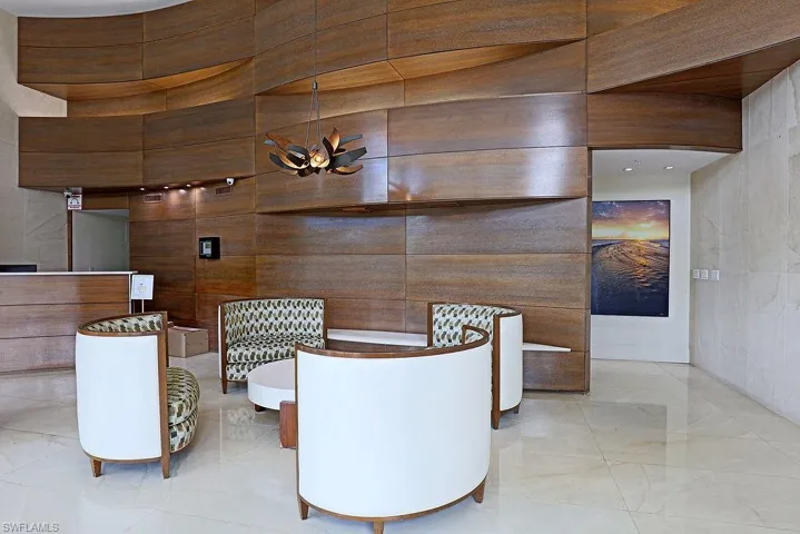 Lobby area featuring wood-finish wall panels with a curved design, a contemporary chandelier, and polished light-toned flooring