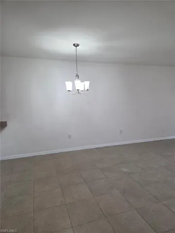 Spare room with a chandelier and baseboards
