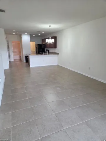 Unfurnished living room featuring light tile patterned floors and a chandelier