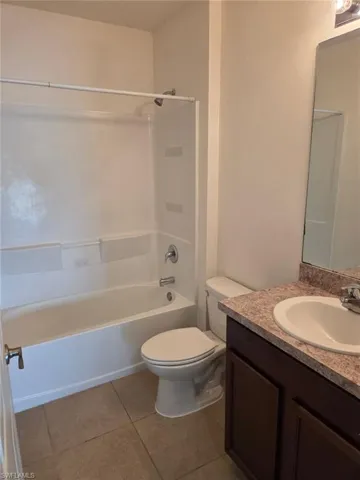 Full bathroom with vanity, washtub / shower combination, and light tile patterned floors