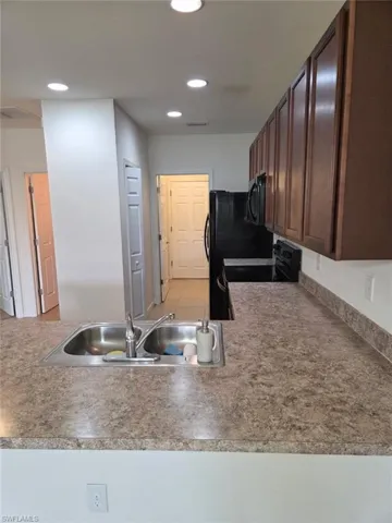 Kitchen with black appliances, recessed lighting, and dark brown cabinetry