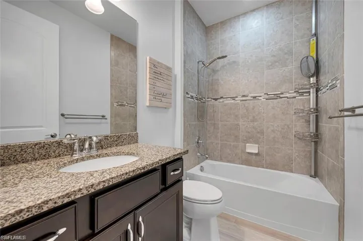 Bathroom featuring vanity, washtub / shower combination, and light wood-style flooring