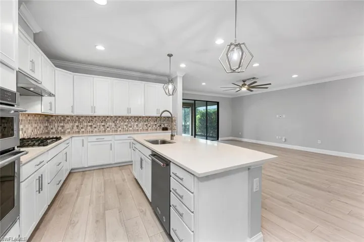 Kitchen featuring White Cabinets,  Quartz Counters, Tasteful Backsplash, and Kitchen Island with Sink
