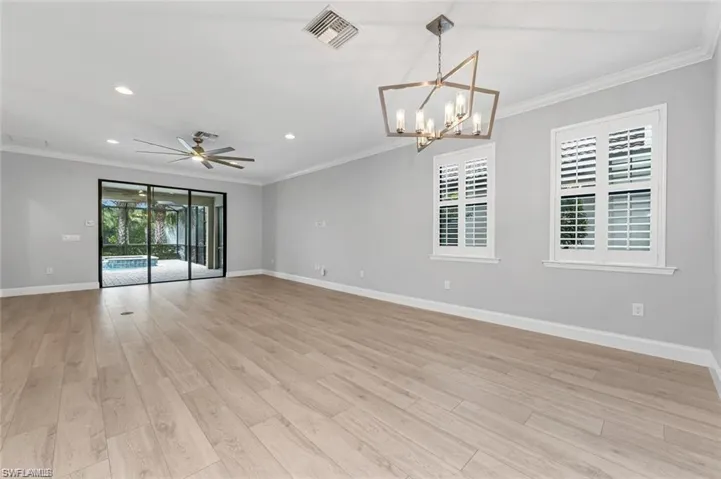 Living room featuring ornamental molding, a ceiling fan, light wood-style flooring, and hanging lights