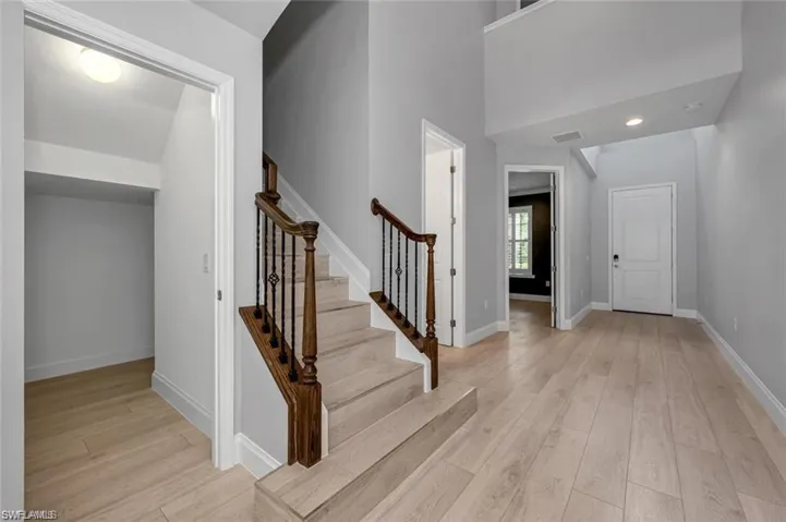 Foyer entrance with light wood-type flooring, a high ceiling, and recessed lighting