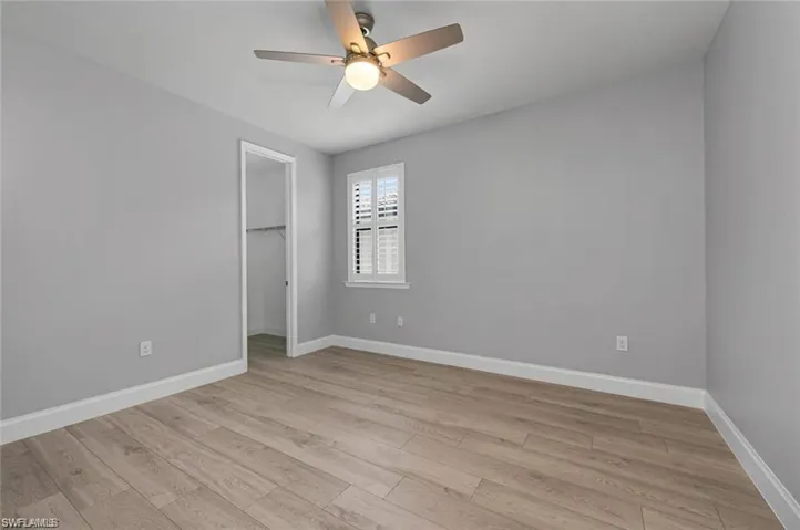 Unfurnished bedroom with a spacious closet, light wood-type flooring, and ceiling fan