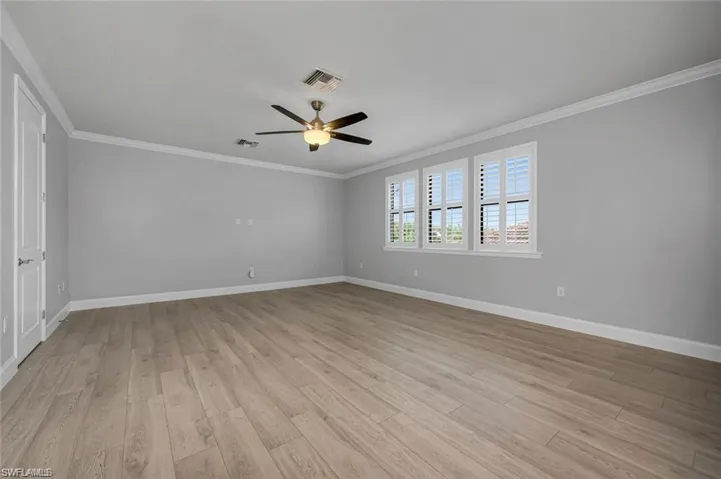 Spare room with crown molding, a ceiling fan, and light wood-style flooring