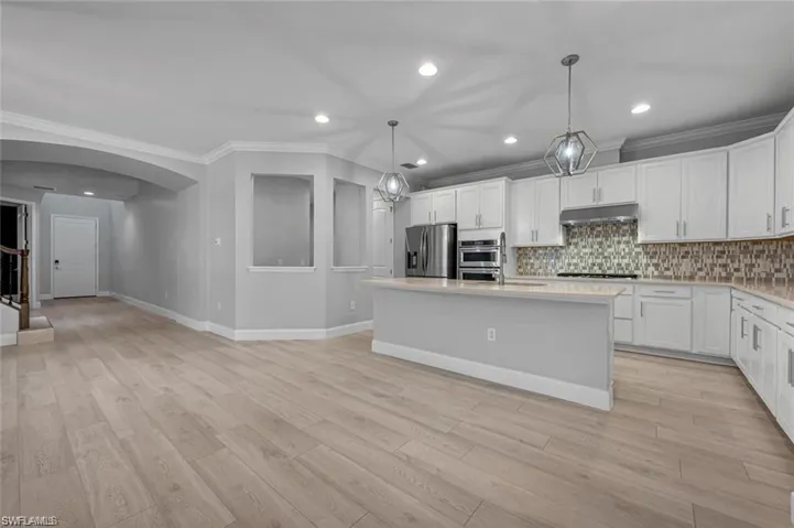 Kitchen w/ White Cabinets, Quartz Counters, Stainless Appliances, and Island w/ Sink
