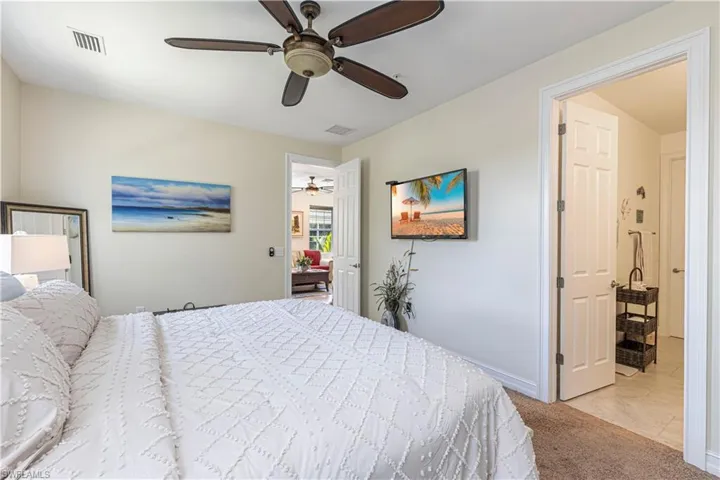 Carpeted bedroom featuring a ceiling fan, visible vents, and baseboards