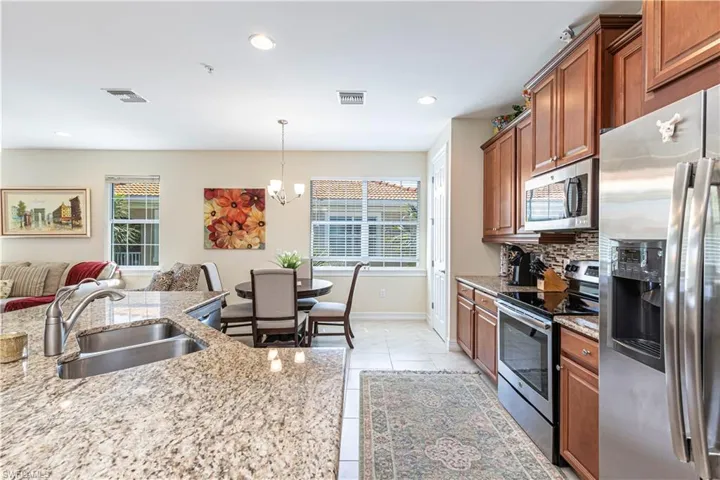Kitchen featuring brown cabinetry, visible vents, stainless steel appliances, and a sink