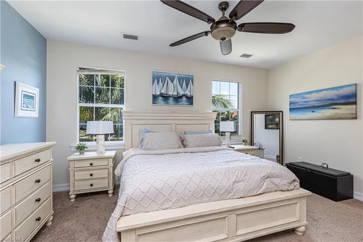 Bedroom with baseboards, visible vents, dark colored carpet, and ceiling fan