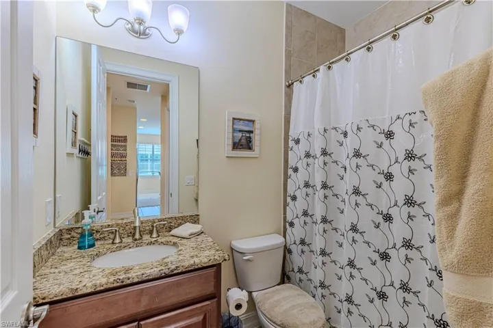 Second full bathroom with visible vents, toilet, a shower with curtain, a notable chandelier, and vanity