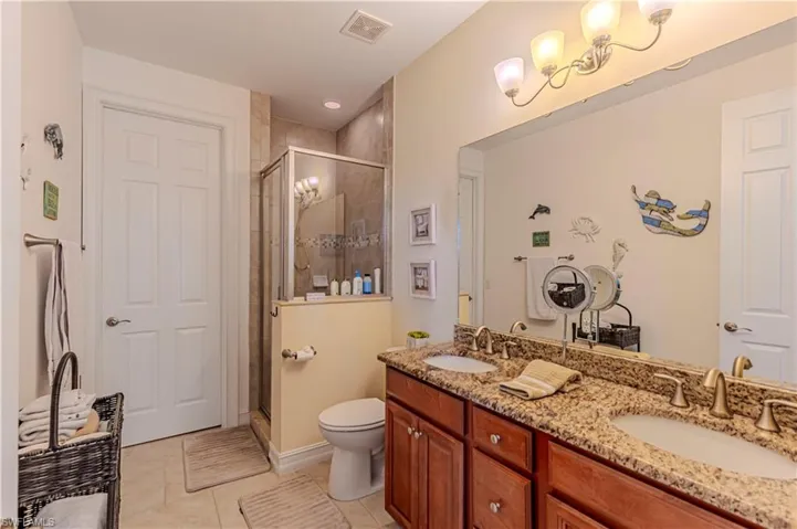 Full bathroom featuring double vanity, visible vents, a stall shower, and a sink