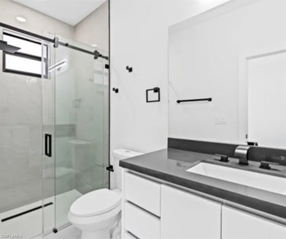 Full bath with vanity, a marble finish shower, and recessed lighting