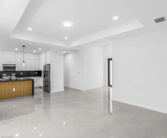 Kitchen with open floor plan, a raised ceiling, modern cabinets, and recessed lighting