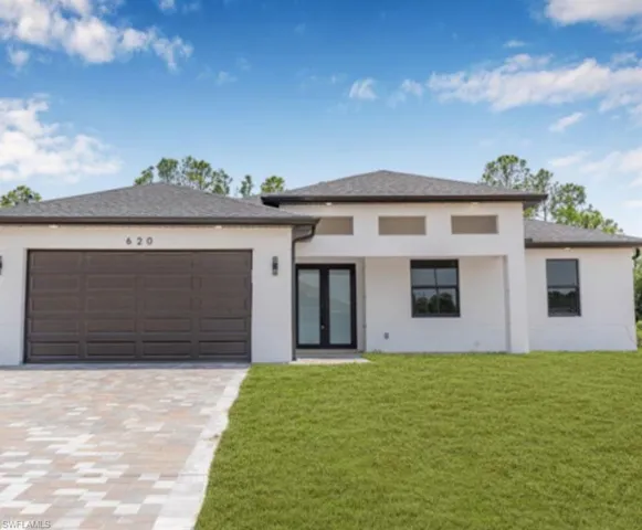 Prairie-style home with a front yard, decorative driveway, an attached garage, and stucco siding