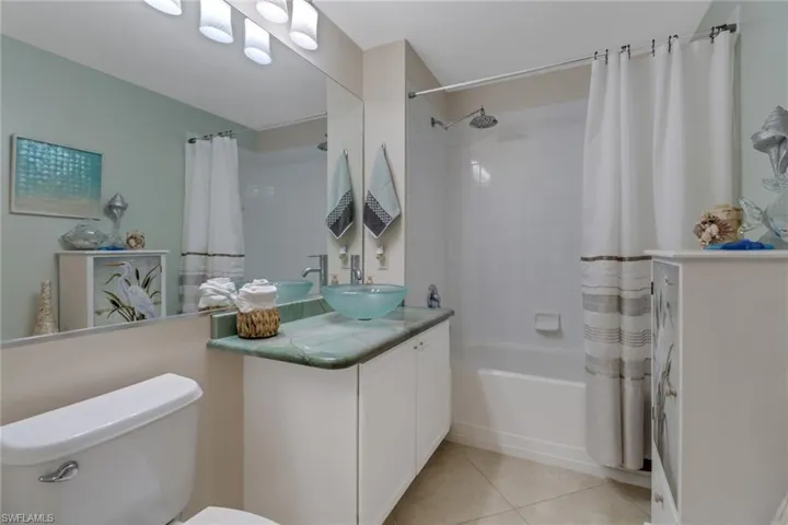 Bathroom featuring vanity, shower / tub combo with curtain, and light tile patterned floors