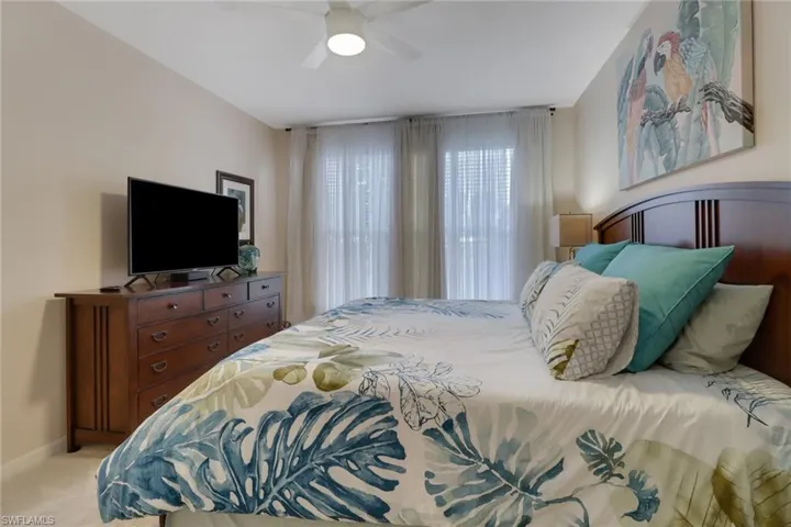 Carpeted bedroom with a ceiling fan and baseboards