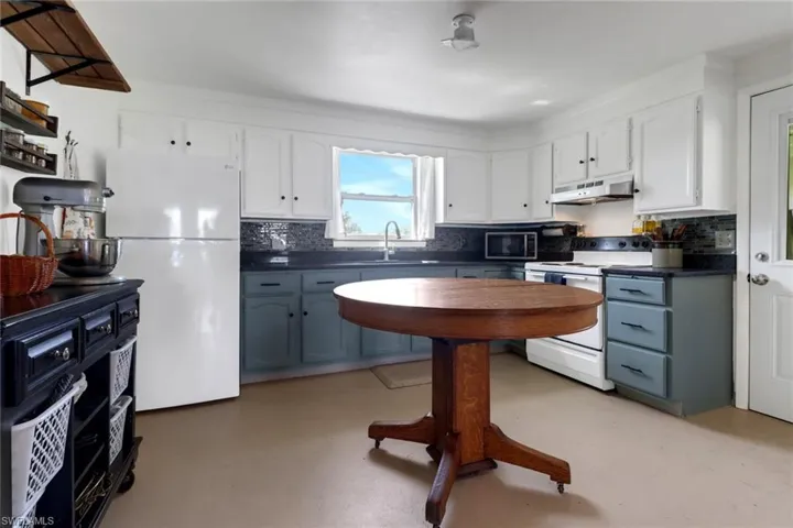 Kitchen with white appliances, white cabinetry, and tasteful backsplash