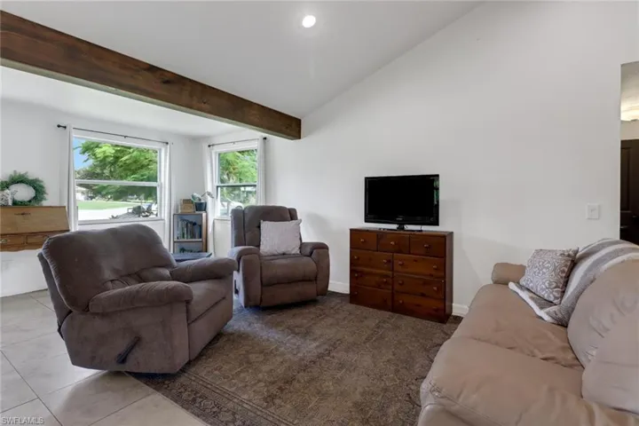 Tiled living room with lofted ceiling with beams