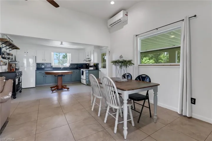 Dining area featuring ceiling fan, light tile patterned floors, a wall mounted air conditioner, and sink