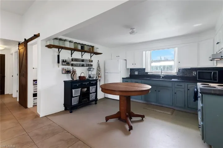 Kitchen featuring white cabinetry, tasteful backsplash, sink, white electric range oven, and a barn door