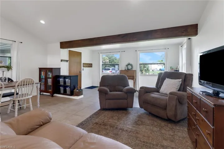 Living room featuring lofted ceiling with beams and light tile patterned flooring