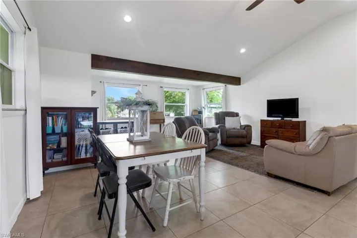 Tiled dining space with ceiling fan and vaulted ceiling with beams